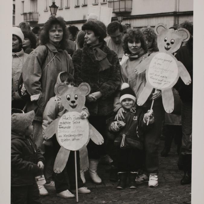 Demonstration: Zur Grün-Lila-Wahlkarawane am 3. März 1990 in Magdeburg demonstrieren Kindergärtnerinnen und Kinder mit Bummi-Transparenten für eine bessere Kinderbetreuung.